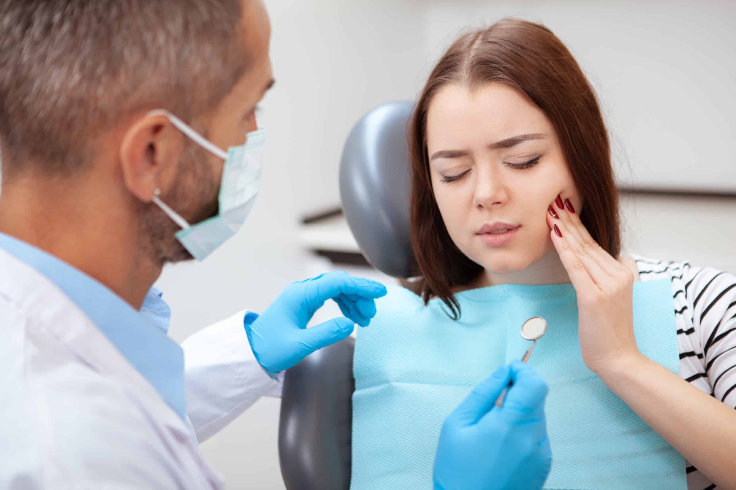 Young woman having toothache, sitting in a dental chair at an emergency dentist clinic